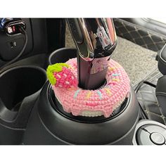 a steering wheel cover with a pink and green donut on it's center console