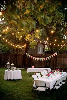 an outdoor party with white table cloths and lights