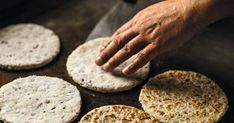 a person reaching for some food on top of a pan filled with tortillas