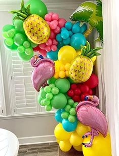 a bunch of balloons that are in the shape of a letter k with pineapples and flamingos on them