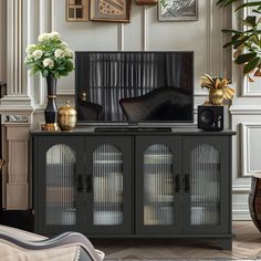 a living room scene with focus on the entertainment center and large plant in vases