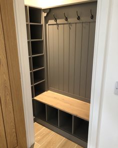 a wooden bench sitting in the middle of a room next to a closet filled with shelves