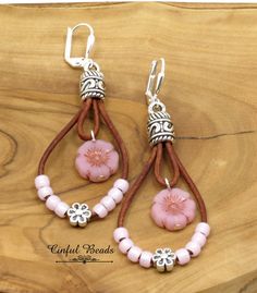 "These charming teardrop boho leather dangle earrings feature a pink Czech glass Hawaiian flower bead hanging on distressed natural brown leather cord. Another strand of leather is embellished with pale pink seed beads surrounding a tibetan style flower bead. The leather has been glued into Tibetan style cord ends. The earrings hang on silver plated brass lever back earwires. The earrings measure 2 1/2\" long from the top of the earwires to the bottom of the longest loop. They are 1\" wide. All Adjustable Pink Teardrop Beaded Earrings, Adjustable Teardrop Flower Earrings, Handmade Adjustable Teardrop Flower Earrings, Adjustable Pink Teardrop Earrings With Ear Wire, Pink Nickel-free Bohemian Flower Earrings, Bohemian Pink Nickel-free Flower Earrings, Adjustable Pink Leather Jewelry, Pink Leather Jewelry Gift, Pink Leather Jewelry As Gift