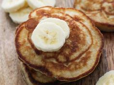 pancakes with banana slices and syrup on a wooden surface, ready to be eaten by someone