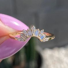 a woman's hand holding a gold ring with three stones on it and a diamond band