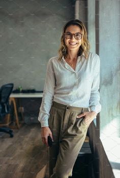 a woman standing in front of a window smiling at the camera with her hands on her hips