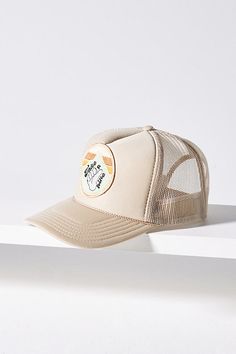 a white trucker hat sitting on top of a shelf next to a wall with an orange sticker