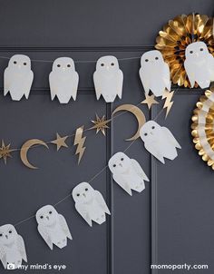 paper owls and stars are hanging on the wall next to a gold star decoration with a golden wreath