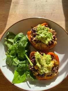 two stuffed peppers with guacamole and lettuce are on a plate