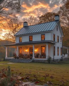 a white house sitting on top of a lush green field under a cloudy sky at sunset