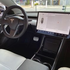 the interior of a tesla car with an electronic display on the dashboard and steering wheel