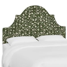 an upholstered headboard with white sheets and green floral print on the top