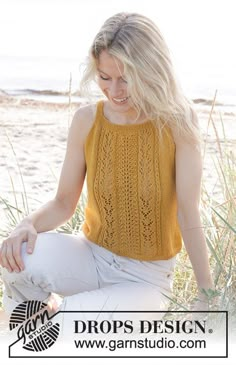 a woman sitting on the ground in front of some grass and sand with her eyes closed