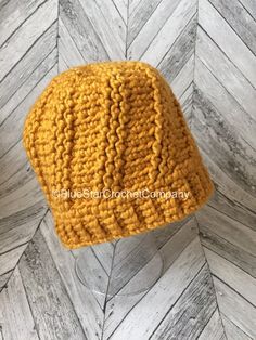 a yellow crocheted hat sitting on top of a wooden floor