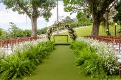 an outdoor ceremony set up with white flowers and greenery on either side of the aisle