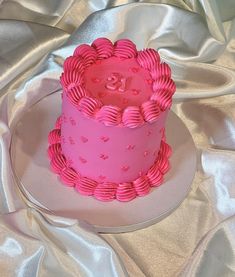 a pink cake on a white plate with silver cloth