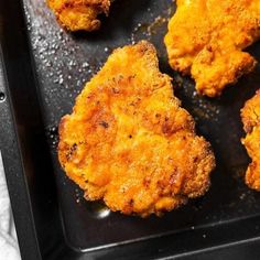 four fried chicken patties on a black tray