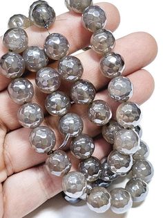 a hand holding a bunch of gray glass beads