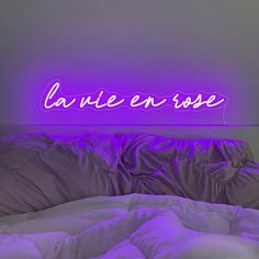 there is a neon sign that says la vie en rose on the wall above the bed