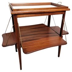 a wooden table with two shelves on each side and one shelf below the top that is holding an object