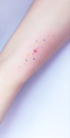 a woman's arm with stars on it and the word love written in pink ink