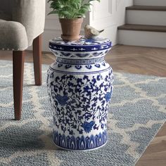 a blue and white vase sitting on top of a rug next to a potted plant