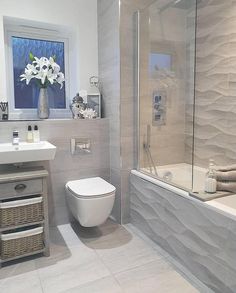 a white toilet sitting next to a bath tub under a bathroom mirror in a bathroom