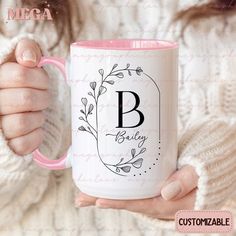 a woman is holding a coffee mug with the letter b on it in her hands