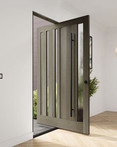 an open wooden door in a white room with wood flooring and potted plant