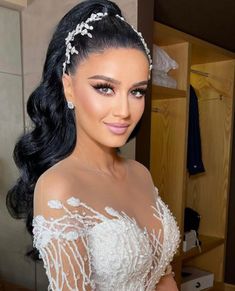 a woman in a wedding dress with long hair wearing a tiara and pearls on her head