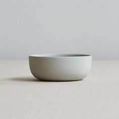 a white bowl sitting on top of a table next to a gray wall and floor