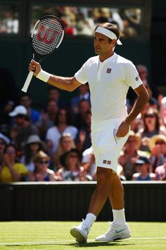 a man holding a tennis racquet on top of a tennis court with people in the background