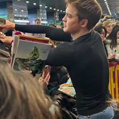 a young man is signing autographs for fans