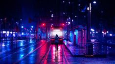 a person sitting on a bench in the rain at night