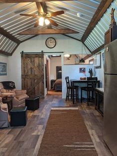 a living room filled with furniture and a metal refrigerator freezer sitting next to a wooden floor