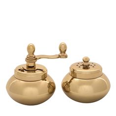 two golden tea kettles sitting side by side on top of each other with handles