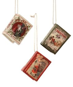 three christmas ornaments hanging from strings on a white background, each with an ornament in the shape of a book