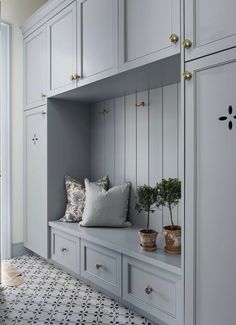 a room with some white cabinets and plants on the ledges, along with other items