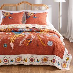 a bed with an orange comforter and pillows