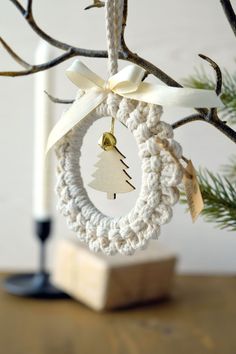 a crocheted christmas ornament hanging from a tree with a candle in the background