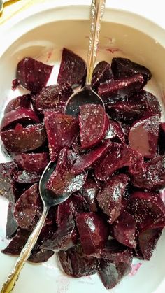 a white bowl filled with beets next to a spoon