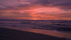 the sun is setting at the beach with waves coming in