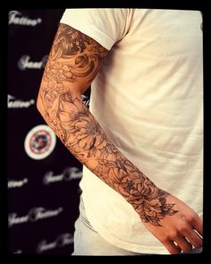 a man with a tattoo on his arm standing in front of a black and white background