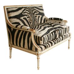 a zebra print chair with gold trimmings on the legs and arms, sitting in front of a white background