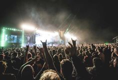 a large crowd at a concert with their hands up in the air and lights on