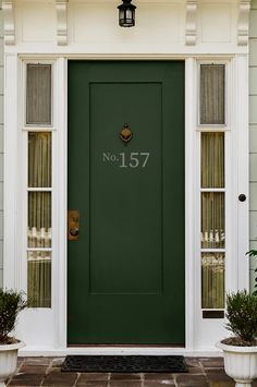 a green door with the number fifteen seven on it and two planters in front