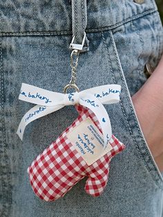 a red and white gingham checkered fabric keychain attached to someone's jeans