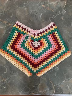 a crocheted shorts with a heart in the middle on a marble floor next to a tile wall