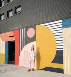 a woman standing in front of a colorful wall