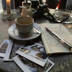 an open notebook, pen and coffee cup sitting on a table with other items around it